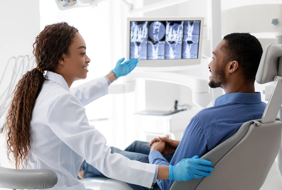 Smiling dentist explaining digital X-ray results to a patient