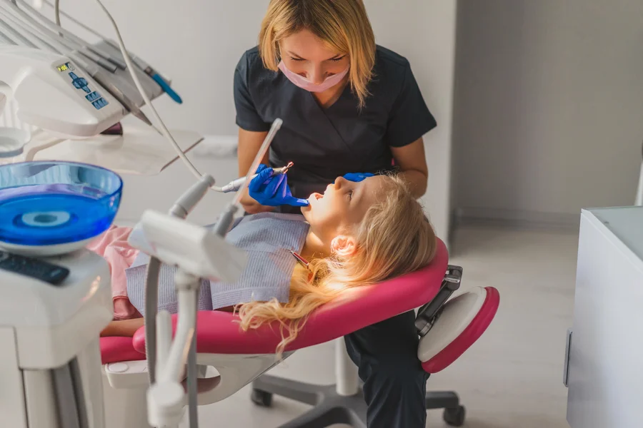 special-needs-dentist-maryland-dental-hygienist-treating-a-young-girl-in-a-pink-chair